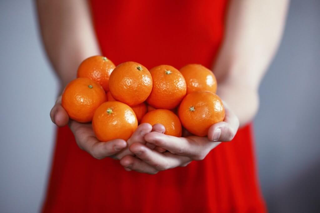 person holding orange fruits