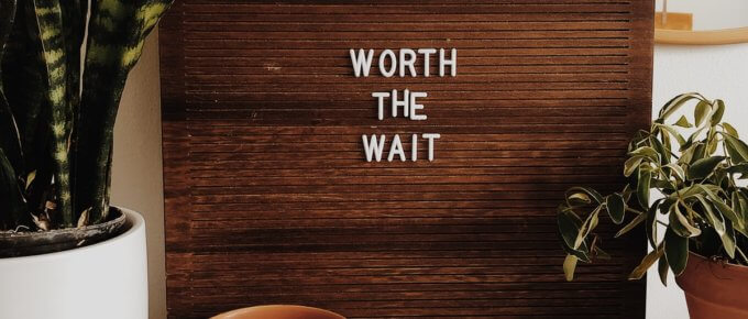 white Worth The Wait sign on brown wooden board