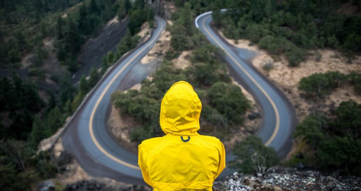 person in yellow coat standing on top of hill